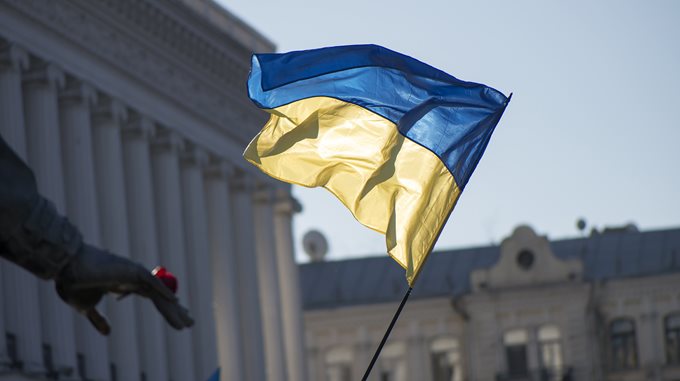 Image of Ukraine flag against sky and buildings
