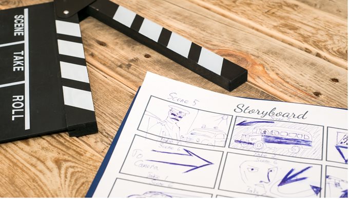 A notepad showing sketches of a storyboard next to a clapperboard