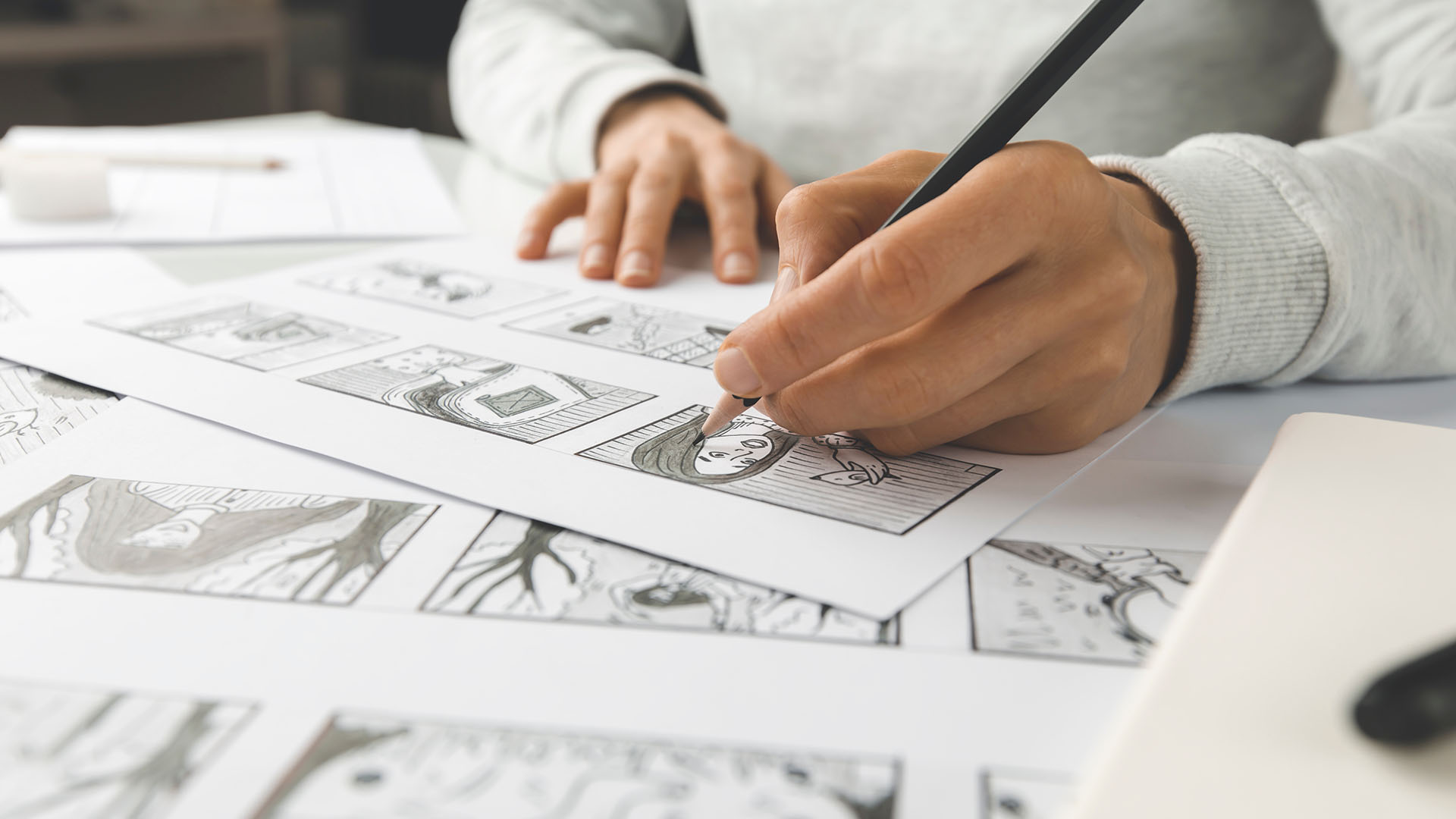 Close-up photograph of the hands of an illustrator drawing a comic panel. Photograph © Oleksandr / Adobe Stock