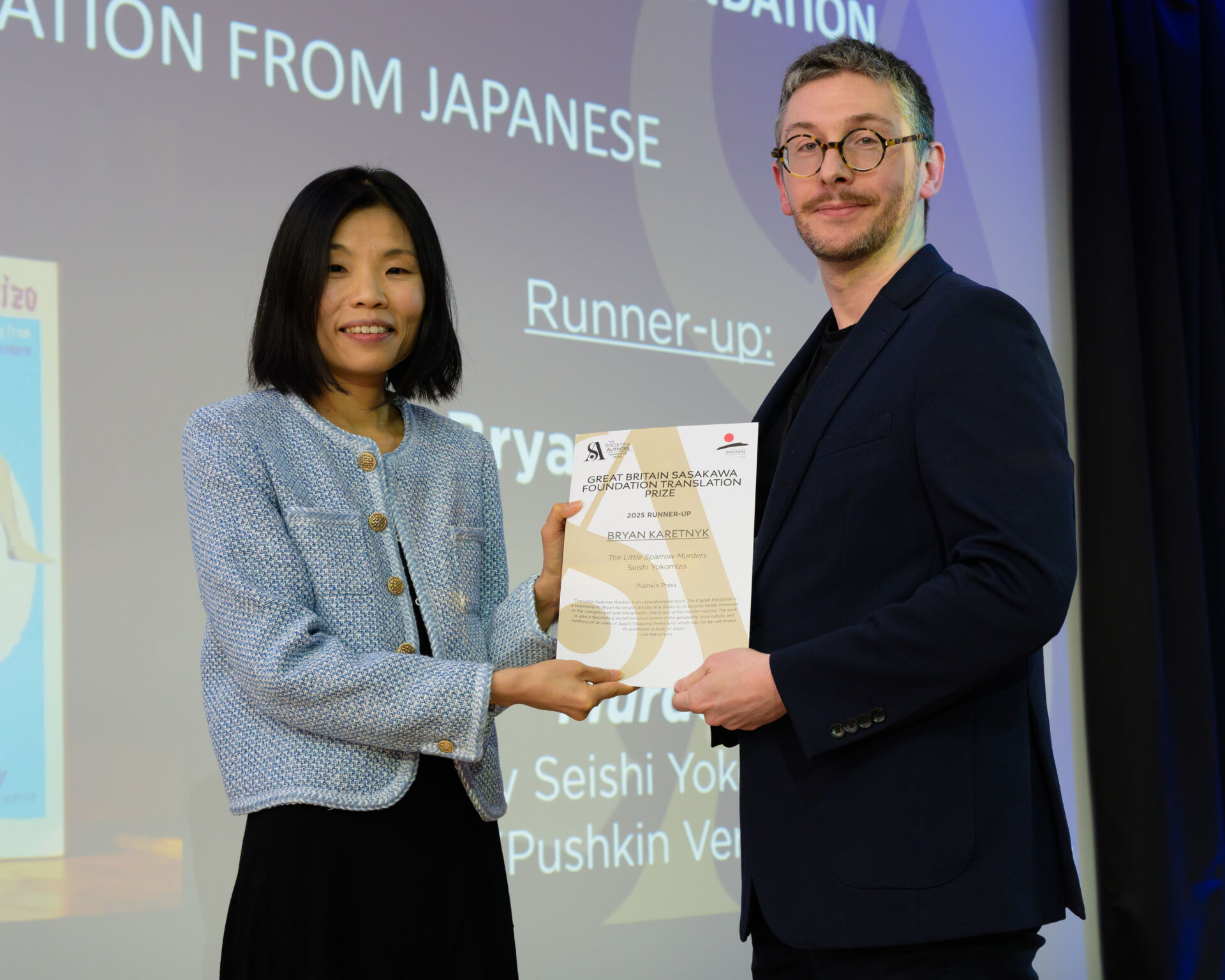 Bryan Karetnyk holding a certifcate with host Fiona Sze-Lorrain