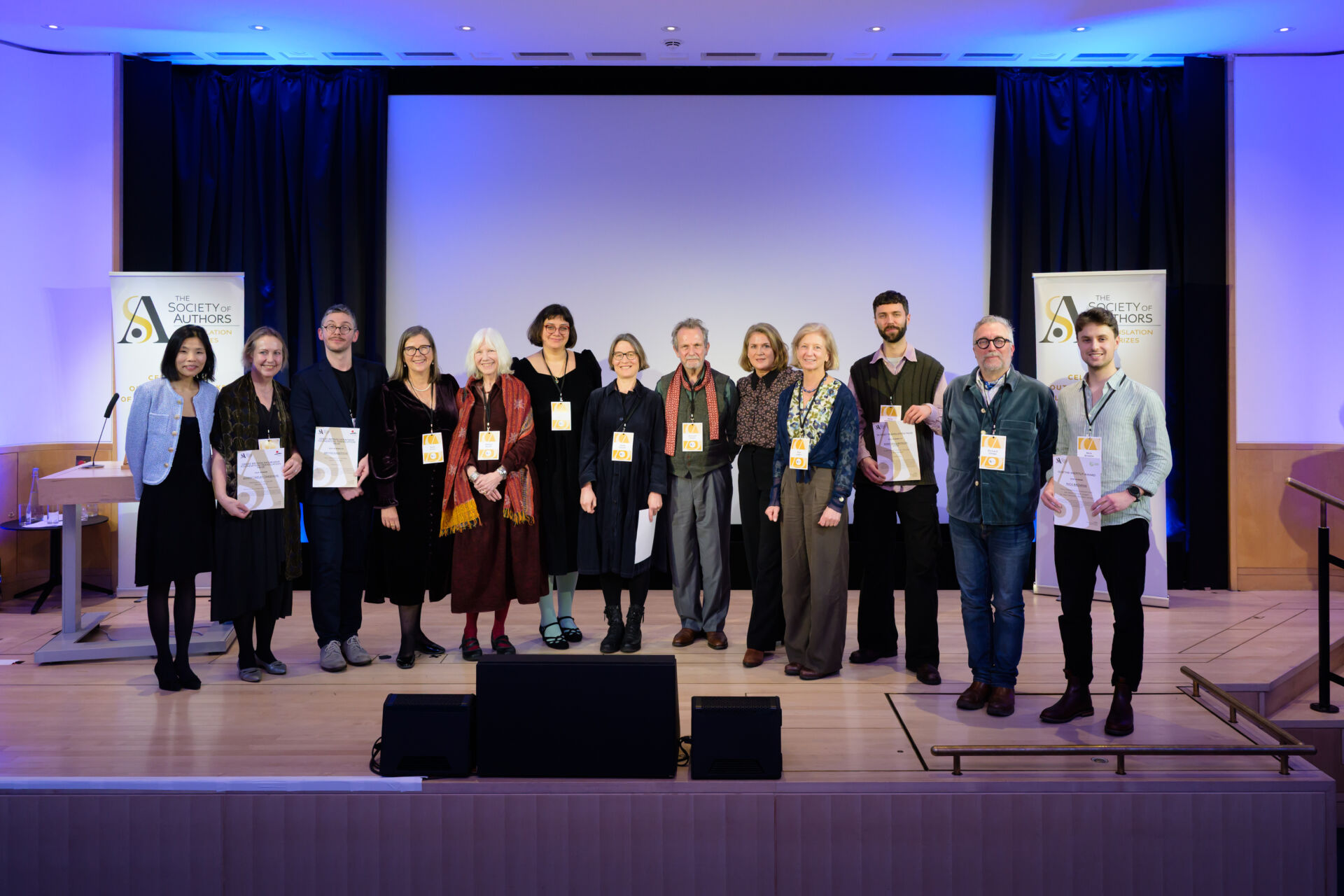 A group of people standing on a stage and holding certificates