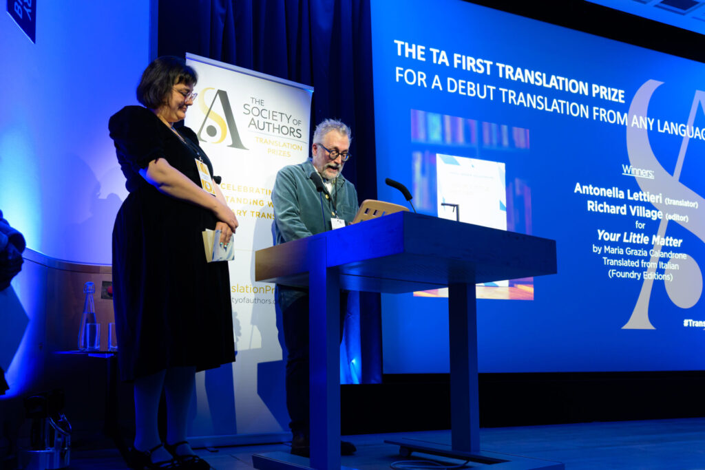Richard Village addressing the audience from the lectern with Antonella Lettieri standing at his side