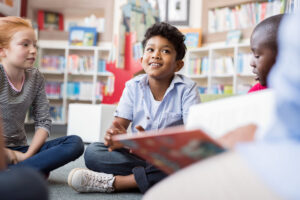 Group of children sitting on floor in circle and listening to a story.