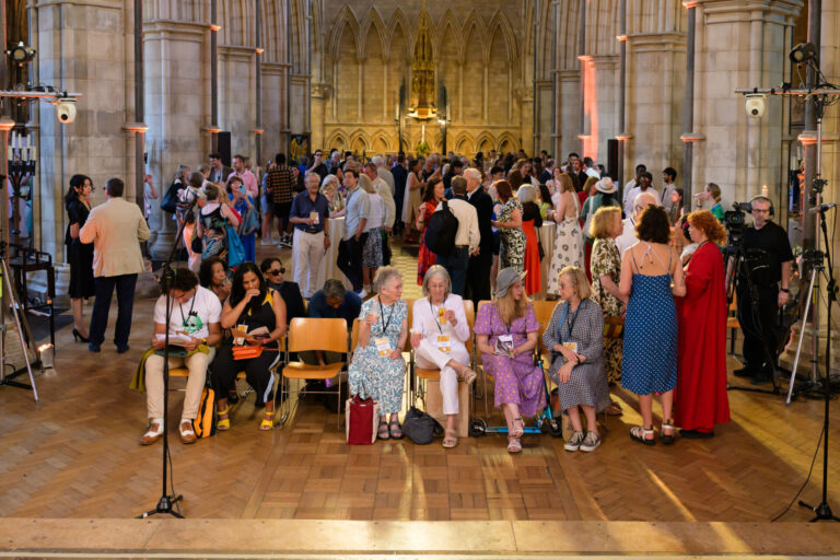 Audience viewed from the stage with lights and camera equipment in shot