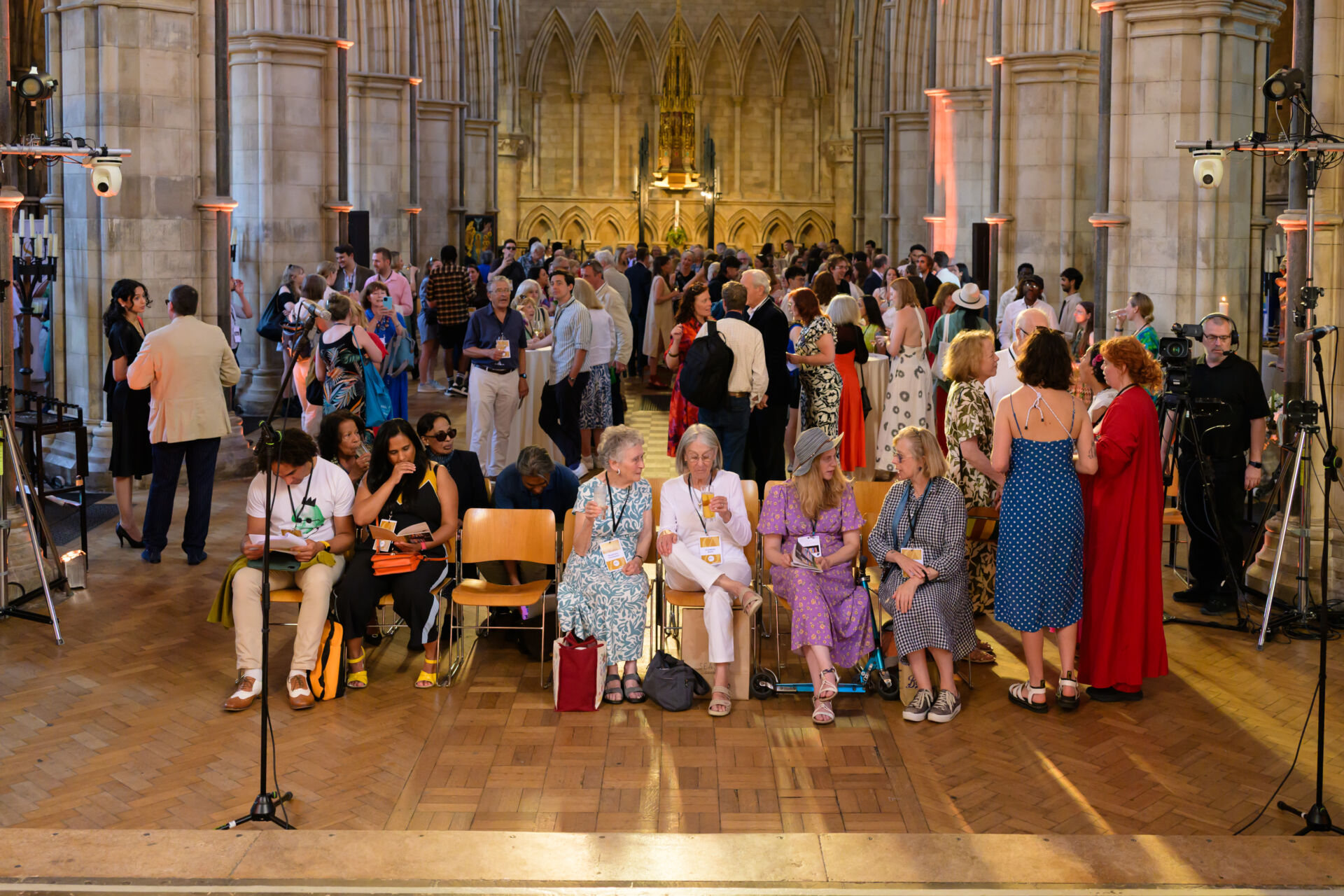 Audience viewed from the stage with lights and camera equipment in shot