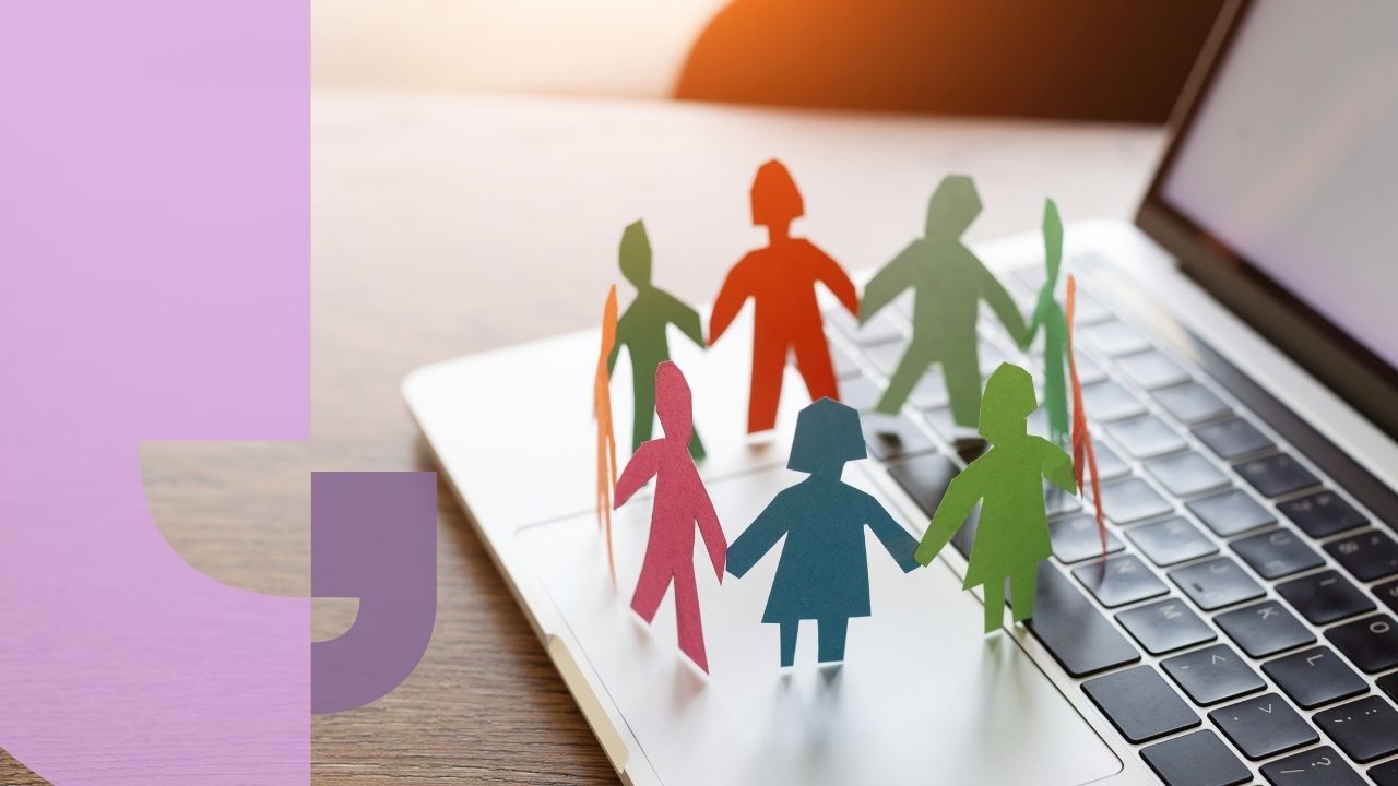 A circle of paper people holding hands on a laptop keyboard