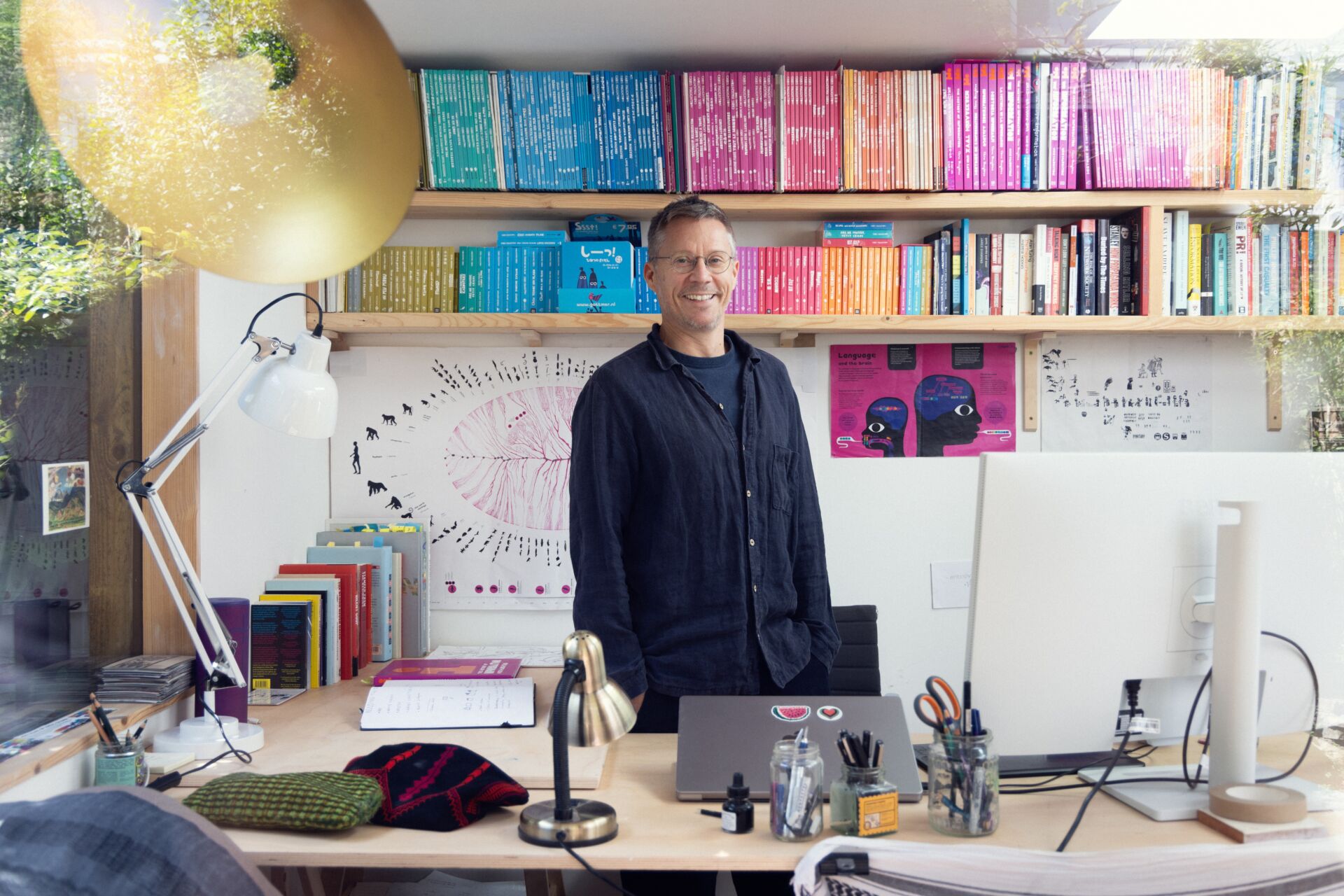 Chris Haughton standing in his studio with a bookshelf behind him and desk in front of him