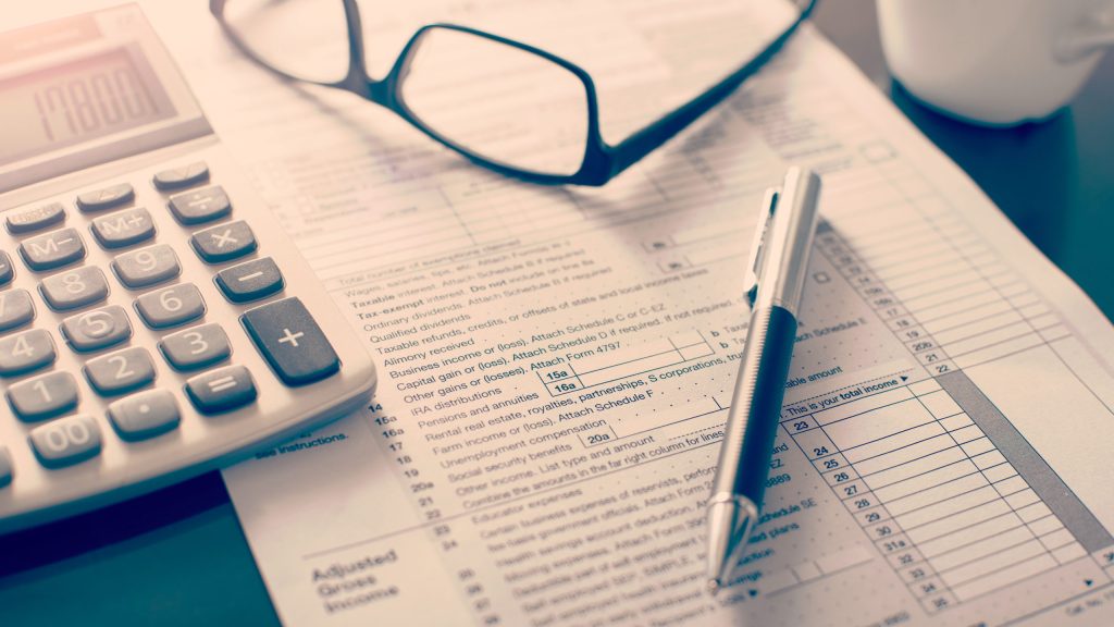 Individual income tax return form, glasses, pen and calculator on desk